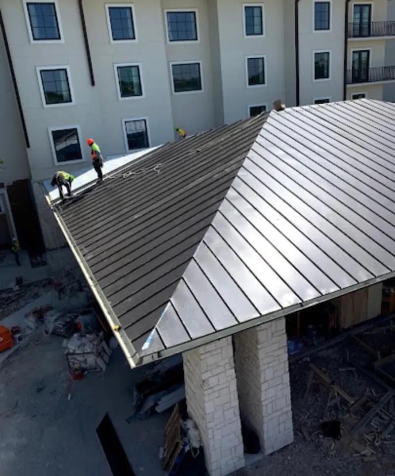 Crew installing standing seam metal roof panels on a commercial project in Edgewood